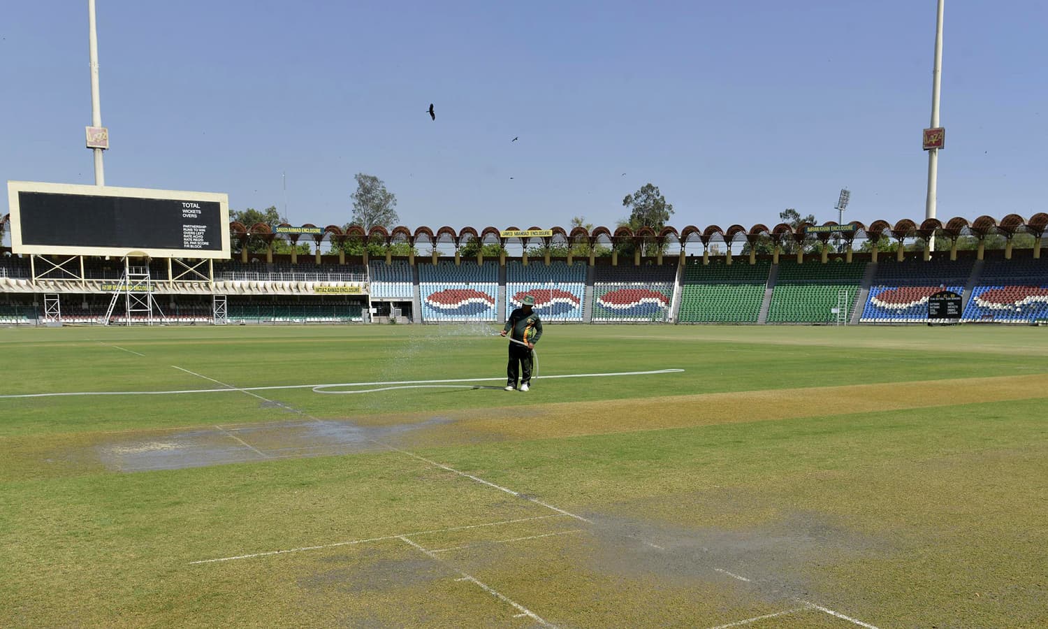 A groundskeeper waters the pitch at the Gaddafi Cricket Stadium in Lahore. — AFP