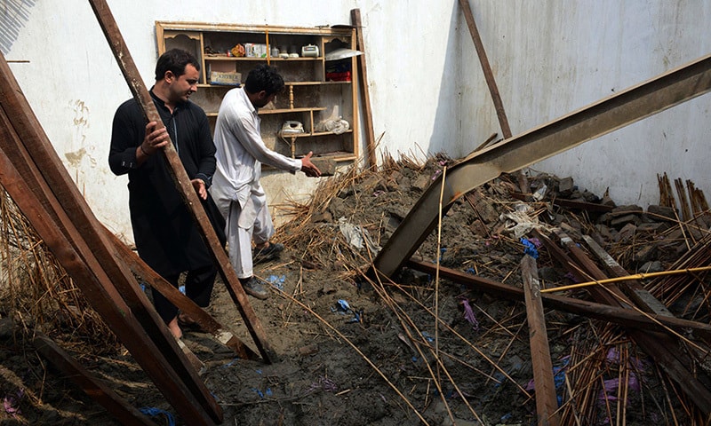 Pakistani residents collect belongings at their home after it was damaged in heavy rain and winds in Peshawar on April 27, 2015. —AFP