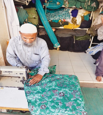 A tailor stitching a tent.