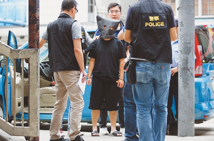 Hong Kong: Police take a suspected member of a gang of kidnappers (centre) through a crime scene reconstruction at a market on Tuesday. The suspect is the only one of six people to have been arrested after they allegedly kidnapped an heiress to a clothing fortune on April 25, freeing her in exchange for a $3.6 million ransom.&mdash;AP