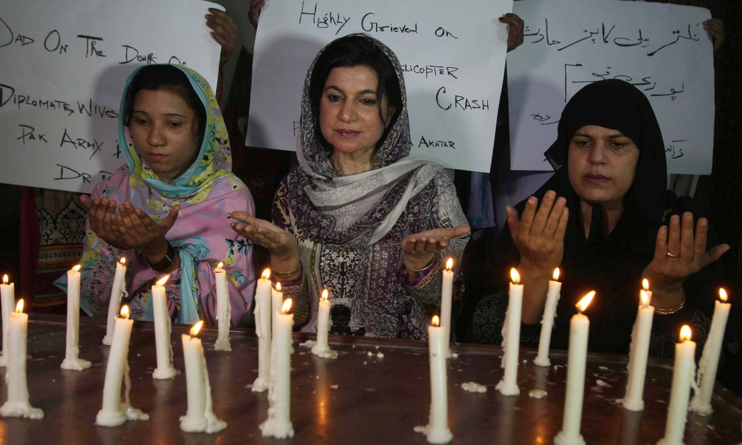 Workers of the civil society light candles and offer prayers for the victims of a helicopter crash, in Multan &mdash; AP