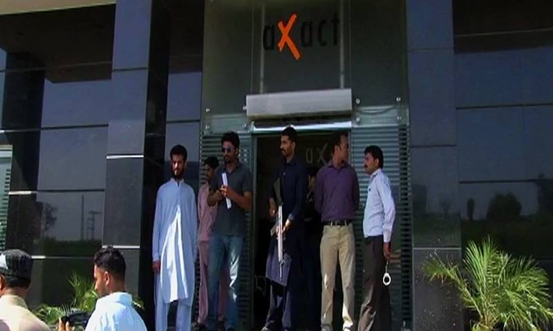 A view of people standing at the entrance of Axact's Islamabad office during the FIA's probe into allegations levelled against the IT company. — DawnNews screengrab