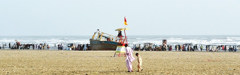 A LIFEGUARD sits on a watchtower on Seaview beach thronged by picnickers.&mdash;White Star