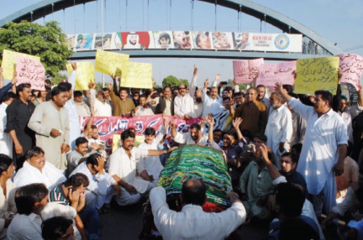 Protesters place the coffin of one of the men on Islamabad Expressway on Sunday. &mdash; Online