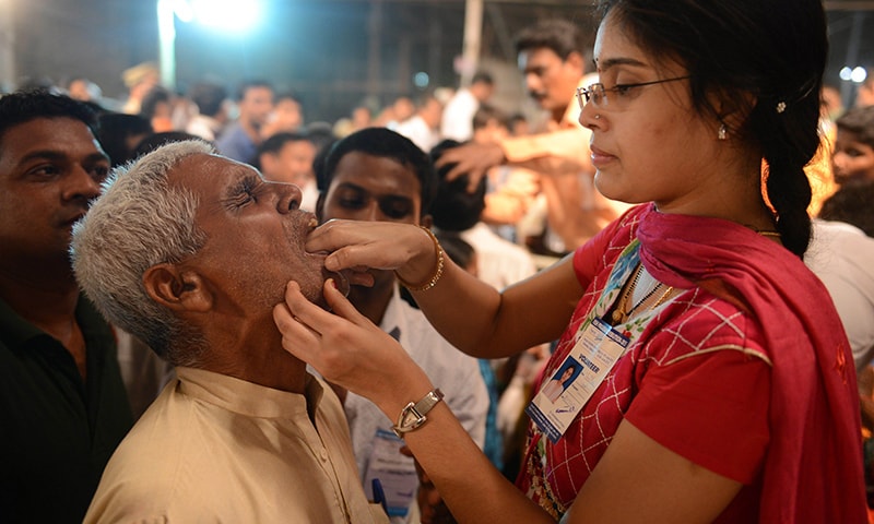 An Indian member of the Bathini Goud family (R) administers 'fish medicine' to a patient.