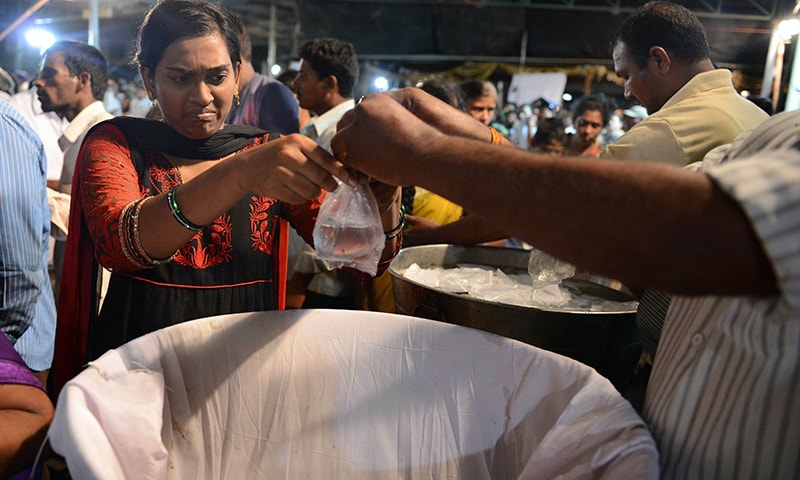 An Indian woman collects live fish prior to receiving fish medicine from members of the Bathini Goud family at the exhibition grounds in Hyderabad