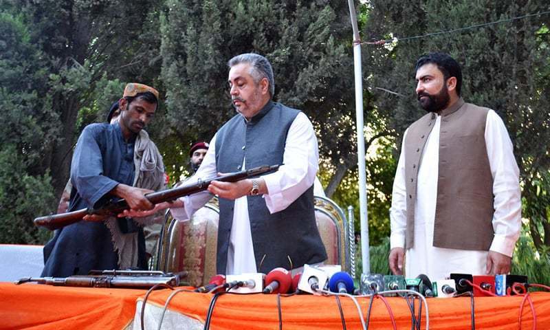 A man belonging to a banned militant group surrenders his arms to Balochistan Irrigation Minister Nawab Jangayz Marri during a press conference Saturday.- Online/File