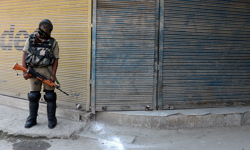 An Indian paramilitary trooper stands guard in front of shuttered shops in Srinagar during a one-day strike called by separatist groups against a recent spate of mysterious killings in India-held Kashmir. ─ AFP