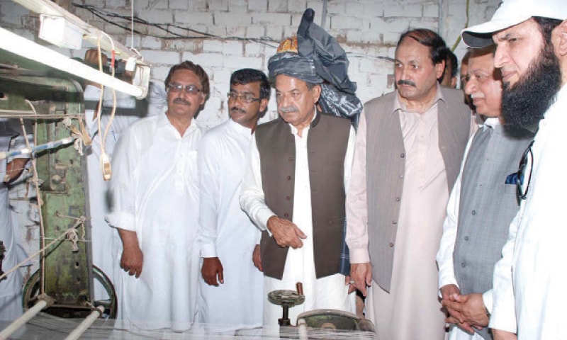 KP Governor Sardar Mahtab Ahmad Khan inspects a power loom after reopening an industrial unit in Bara, Khyber Agency, on Wednesday. — Dawn