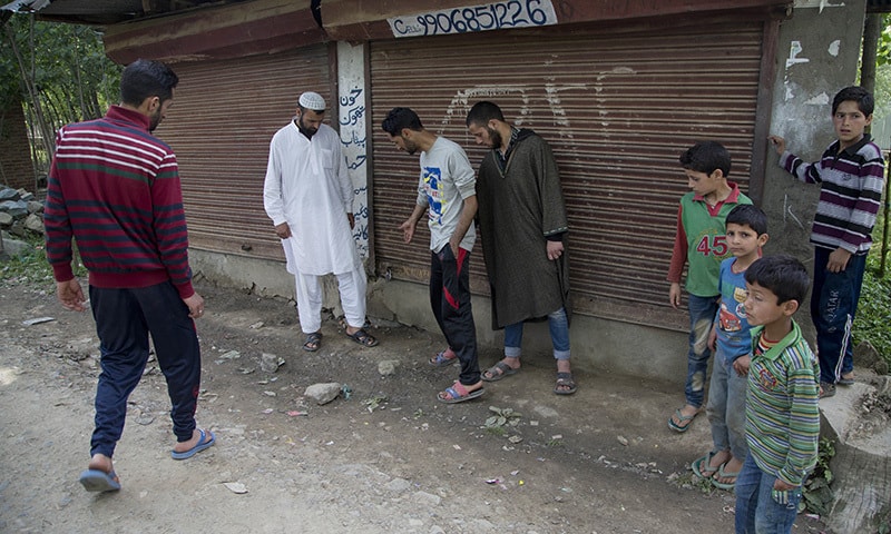 Relatives and neighbors of Aijaz Ahmed Reshi point towards blood stains outside a shop where Aijaz was shot in Mundji, in Indian controlled Kashmir. ─AP/File