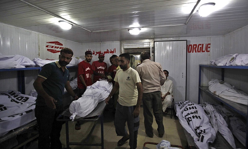 Men move the body of a deceased, who died due to intense hot weather, at Edhi morgue.- Reuters