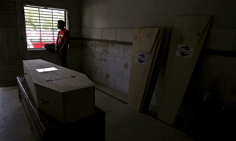 An Edhi volunteer sits beside a window as he waits for relatives of a deceased, who died due to intense heat, to collect the body.- Reuters An Edhi volunteer sits beside a window as he waits for relatives of a deceased, who died due to intense heat, to collect the body.- Reuters