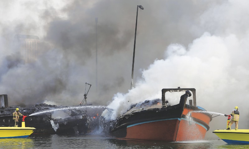 Dubai: Smoke rises from two boats as fire-fighters spray water to extinguish the fire.—AP