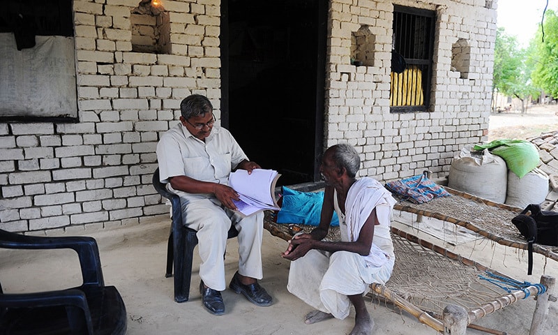 Ram Janam Mauriya (R) speaks with activist Lal Bihari in the Azamgarh district of the state of Uttar Pradesh. For the last two years Ramjanam Mauriya has made countless journeys to Azamgarh magistrate's office in northern India, laden with stacks of documents to prove he is not a ghost. &mdash;AFP