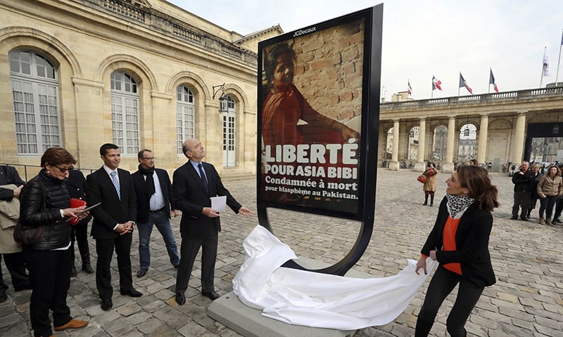 Mayor Alain Juppe (L) unveils a poster in the courtyard of the City Hall in the southwestern French city of Bordeaux in honour of Asia Bibi in March 2015. ─ AFP/File