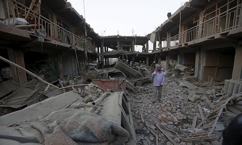 An Afghan man talks on his phone at the site of a suicide truck bomb attack in Kabul. ─ Reuters