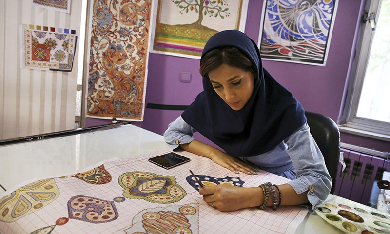 An Iranian woman sketches and paints carpet patterns at a workshop in the Cultural and Artistic Carpet Foundation of Rassam Arabzadeh in Tehran, Iran. - AP Photo/Vahid Salemi