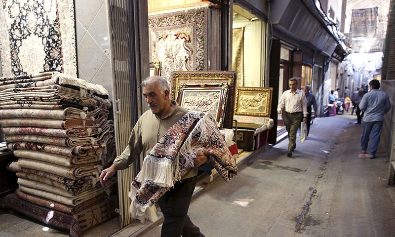 An Iranian man carries a carpet through Tehran's old, main bazaar, Iran. - AP Photo/Vahid Salemi