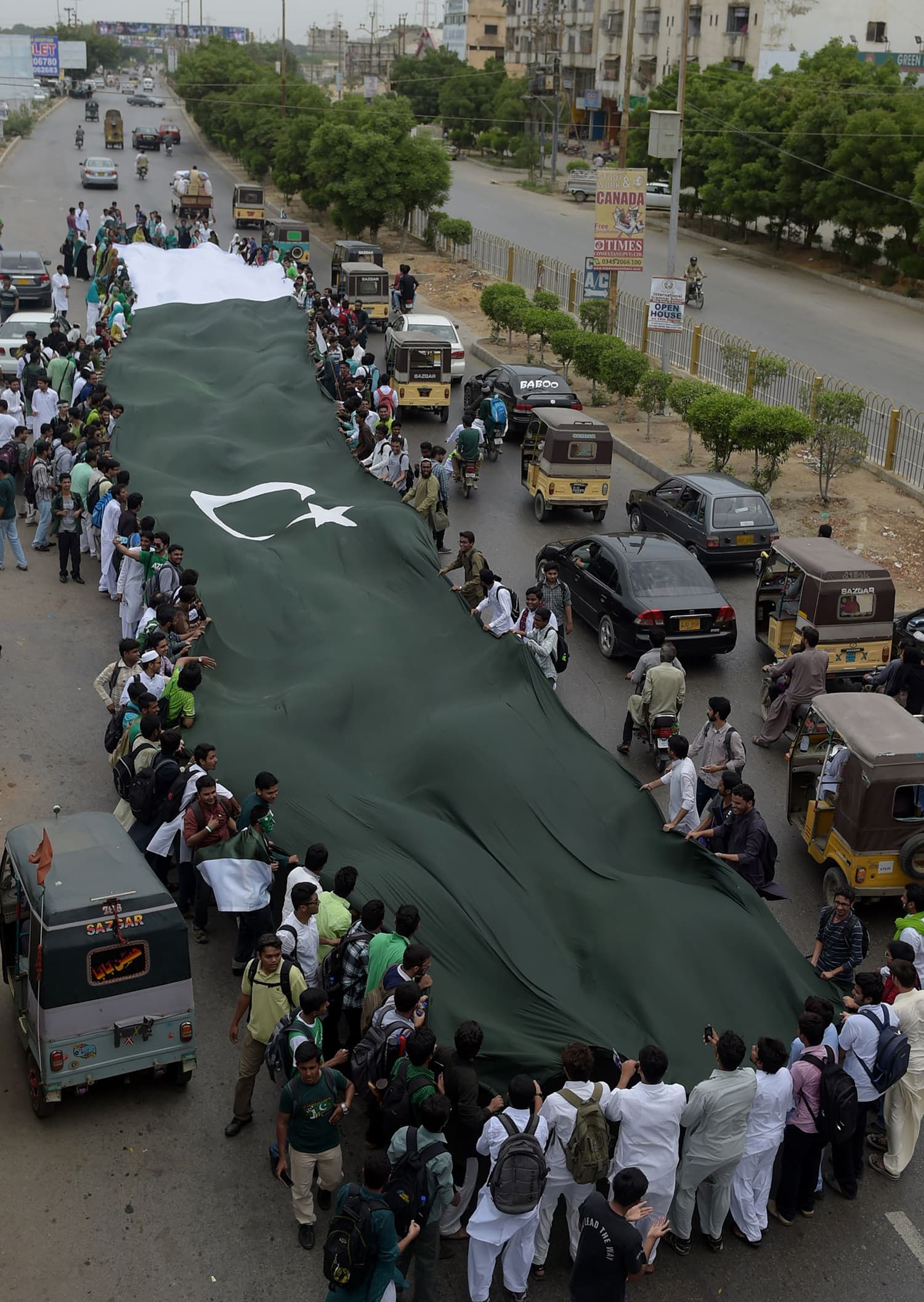 Students carry a national flag as they march on a street ahead of the country's forthcoming Independence Day celebrations in Karachi. — AFP