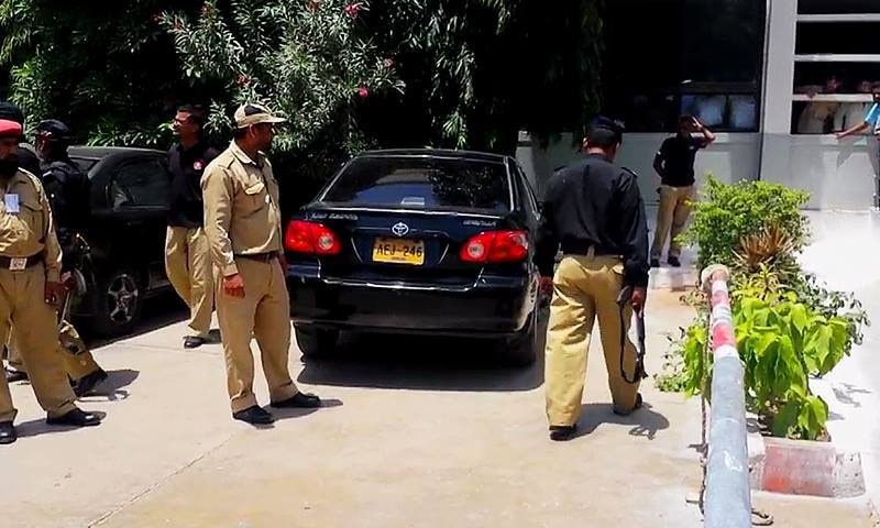 A view of security personnel standing next to Rashid Godil's vehicle which came under attack in Bahadurabad area of Karachi.  — DawnNews screengrab