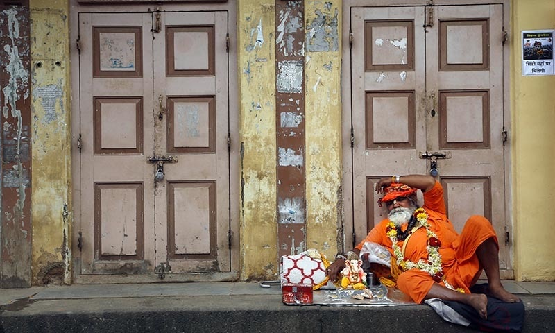 A Hindu holy man rests outside a closed shop during the Kumbh Mela at Trimbakeshwar in Nashik, India. ─ AP