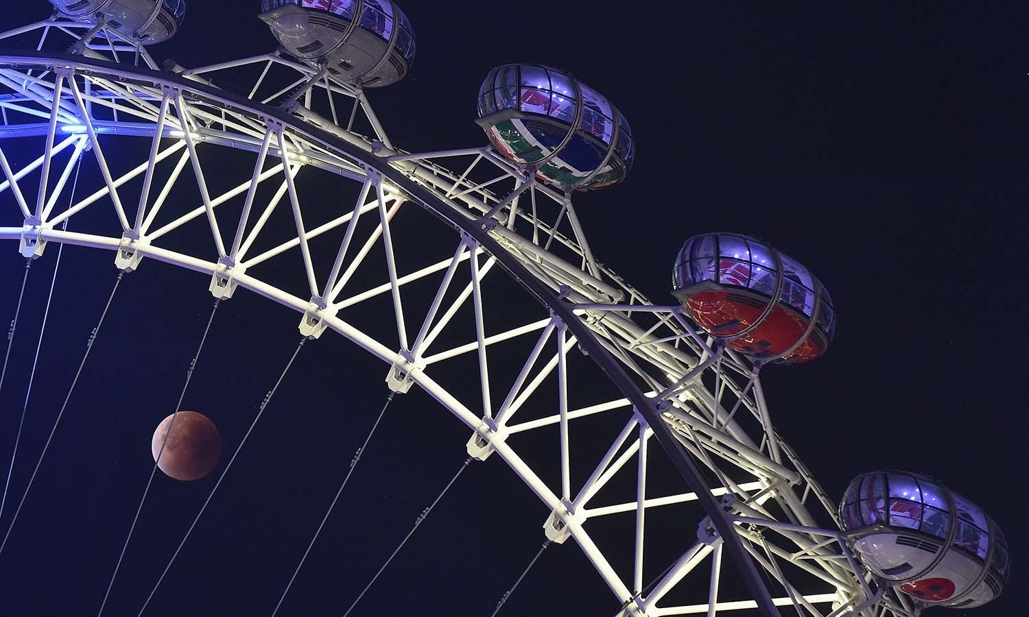 A "supermoon" is seen during a lunar eclipse behind pods of the London Eye wheel in London. — Reuters