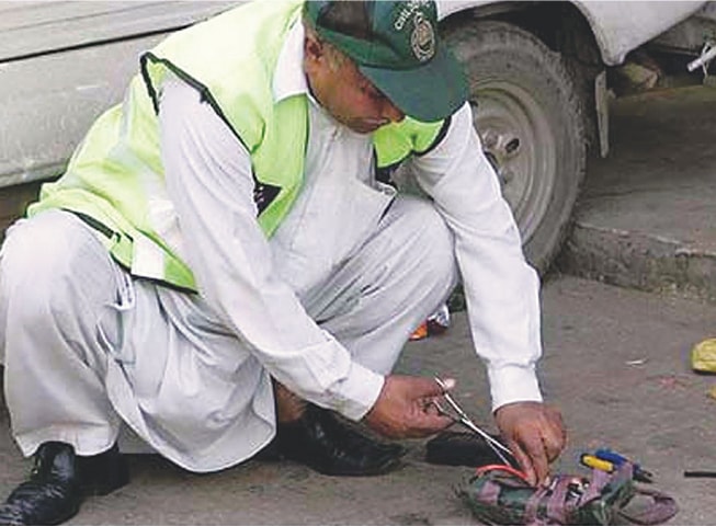 A bomb disposal squad official examines the IED that was lobbed into the parking area of the Counter Terrorism Department in the early hours of Monday.&mdash;PPI