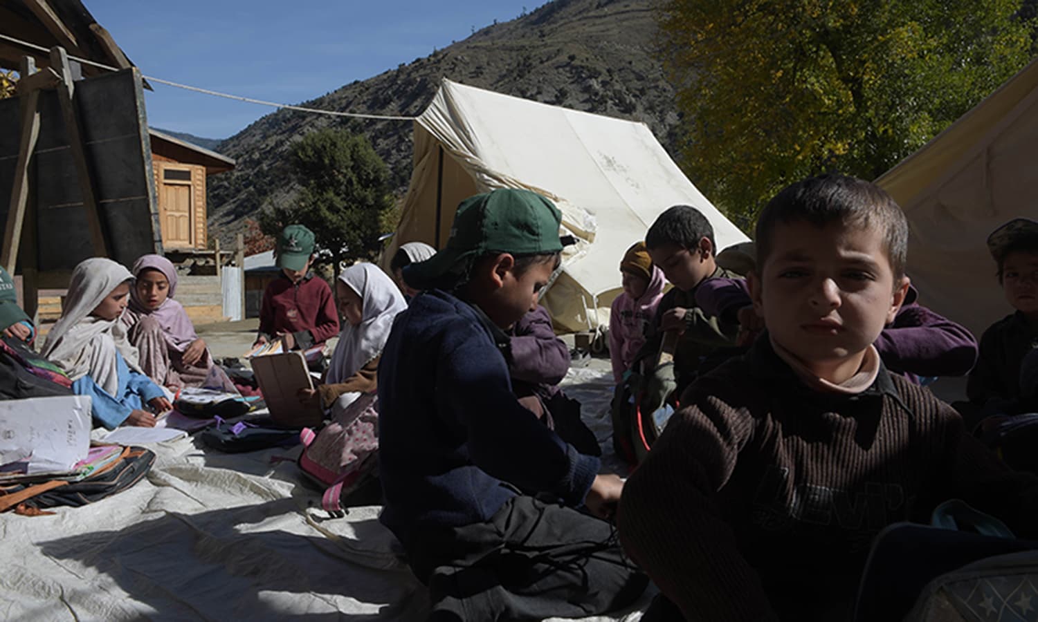 Children attend a class outside an earthquake-damaged school in Brun. ─ AFP