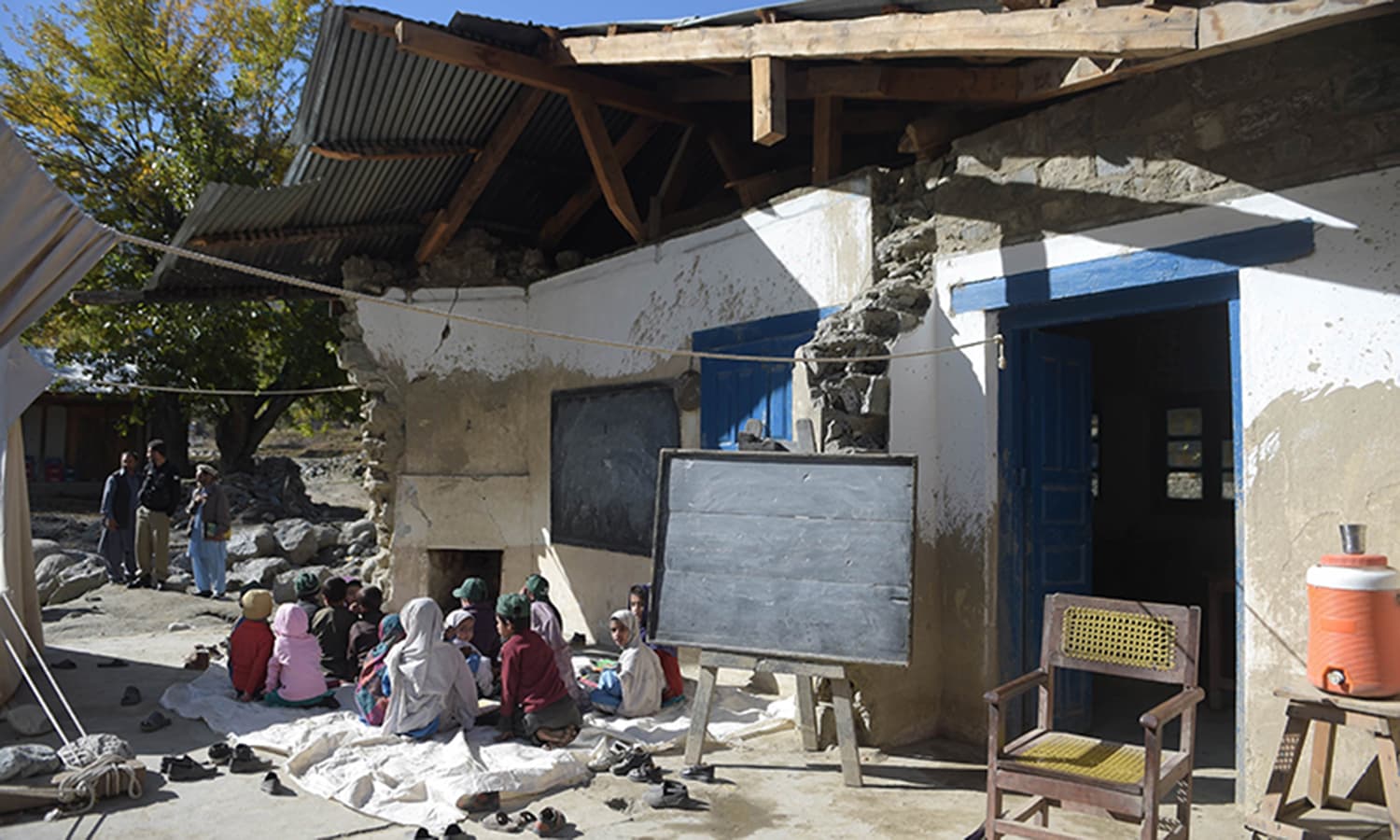 Children attend a class outside an earthquake-damaged school in Brun. ─ AFP