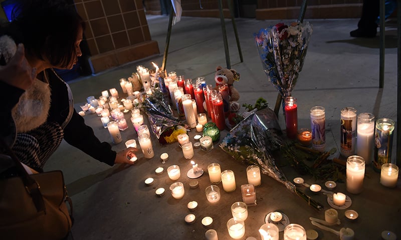 People leave candles at a memorial at the San Manuel Stadium in San Bernardino, California. — AFP