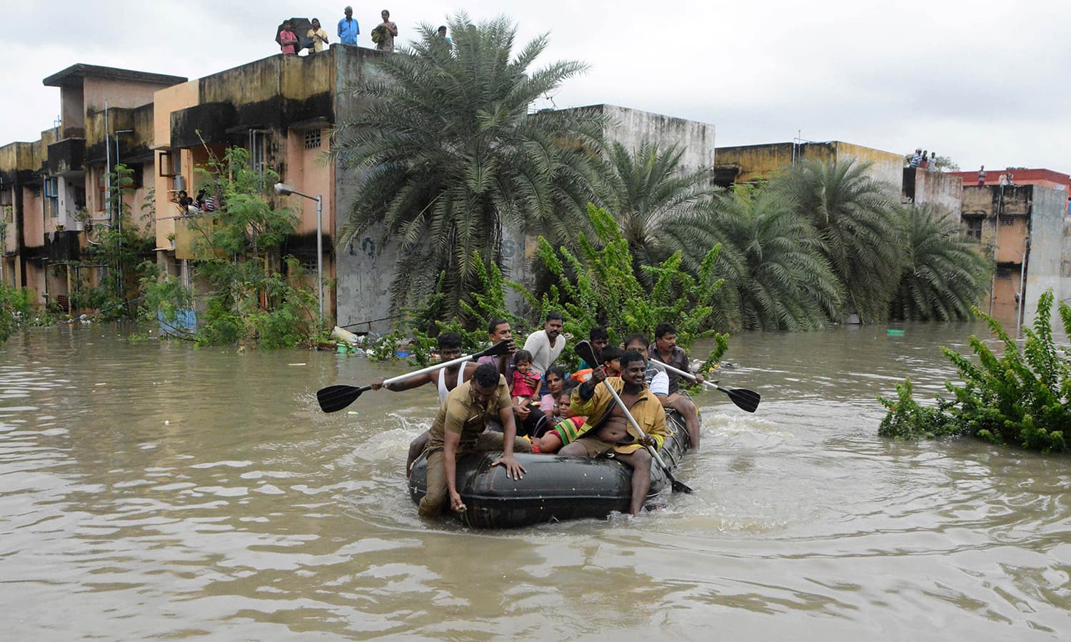 Indian rescue personnel and police officials paddle an inflatable boat through floodwaters as they evacuate residents in Chennai on December 2, 2015. — AFP