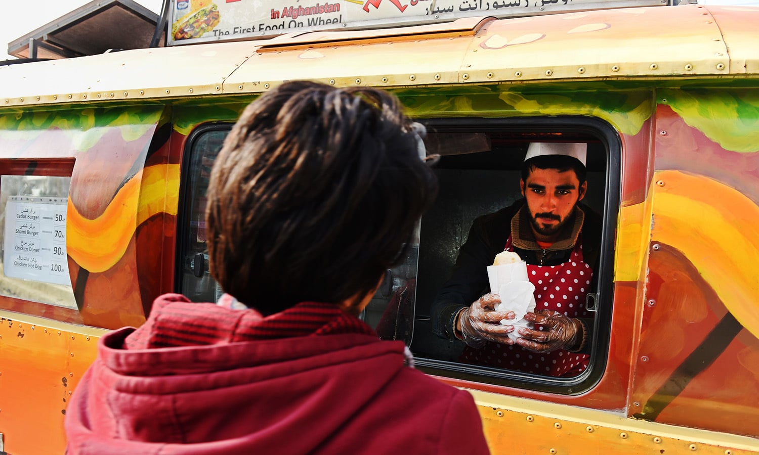 In this photograph taken on December 27, 2015, an Afghan customer buys a burger from a Lazeez food truck in Kabul.&mdash;AFP
