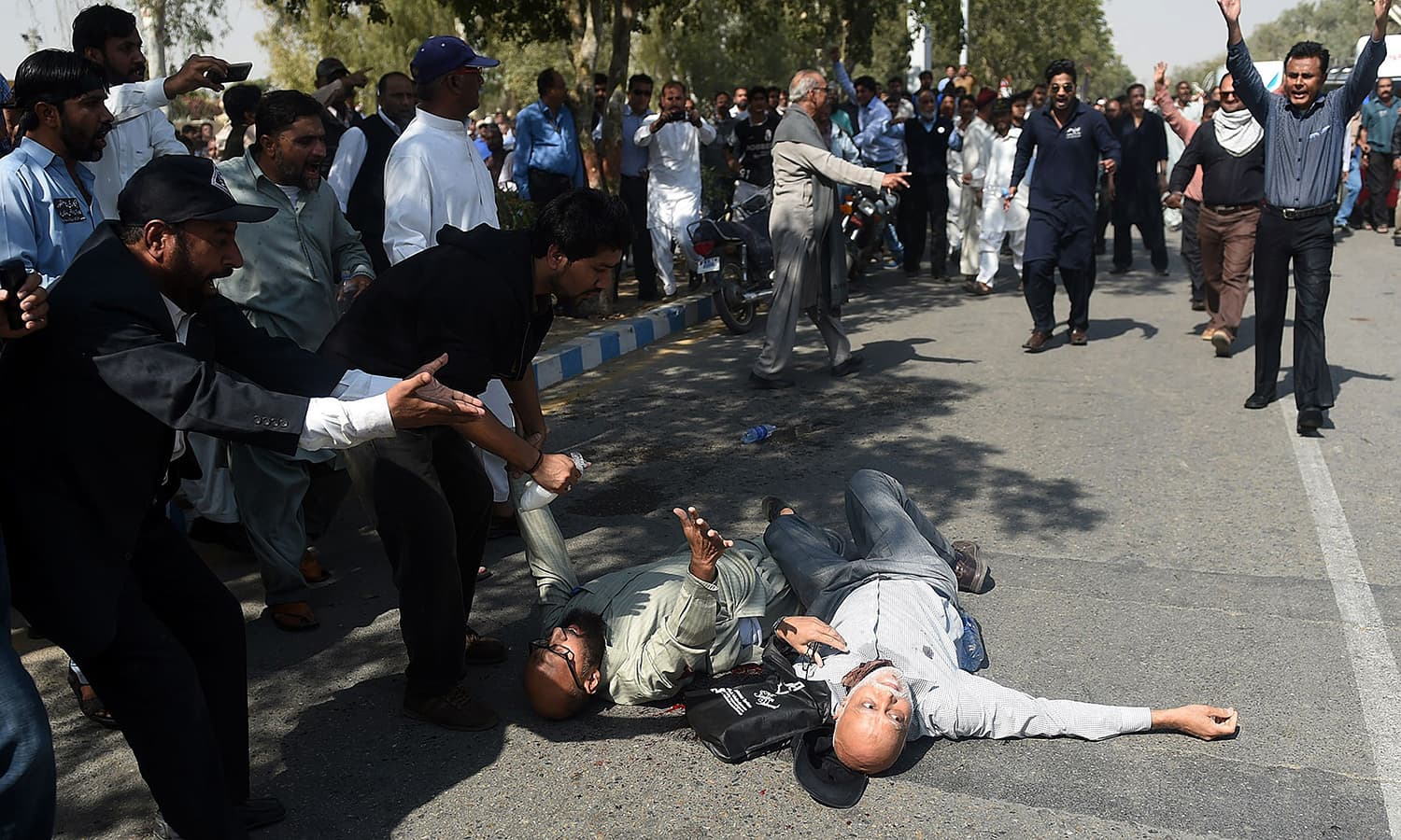 Protesting PIA employees gather around injured colleagues who were hit by bullets. ─AFP