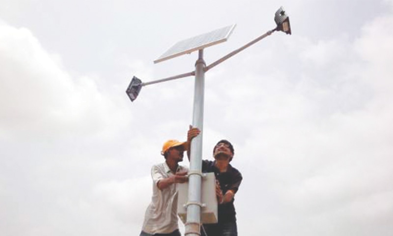 Mechanics mount a solar panel on a pole in Jati village in the coastal district of Thatta in Sindh.—Reuters file photo