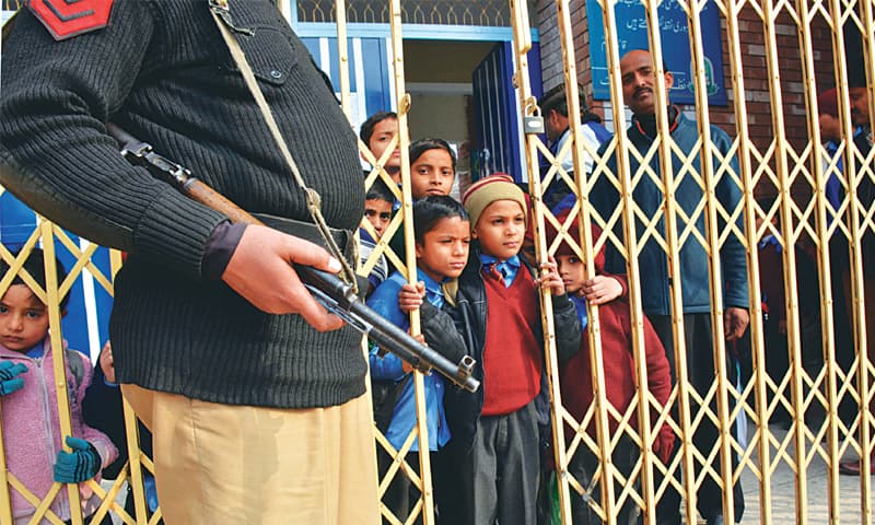 Children peep through the iron grill installed at a school as part of fresh security measures on the first day after an extended winter break