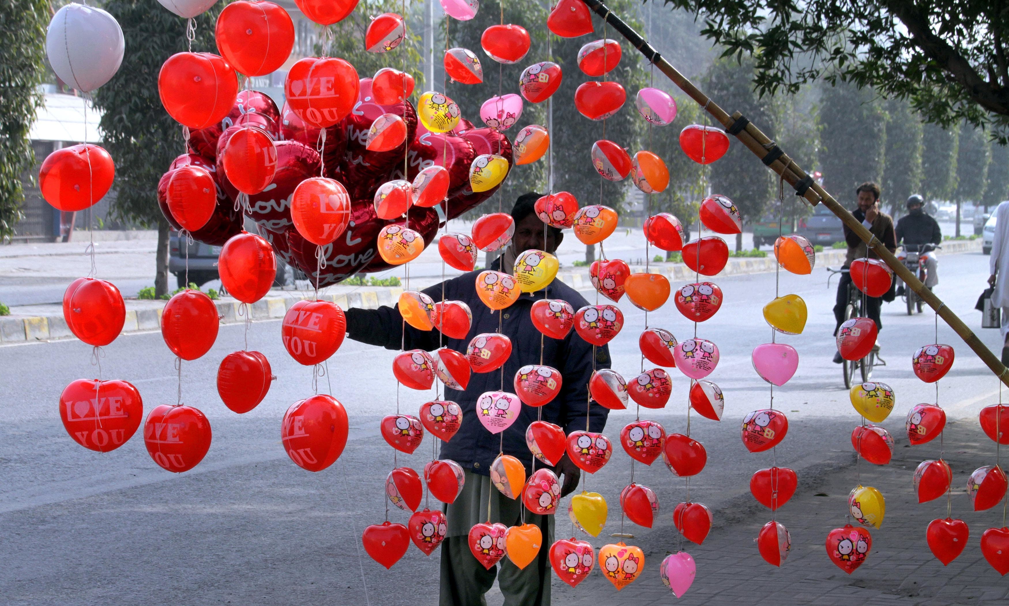 A vendor arranges heart-shaped balloons along the roadside to attract customers. —AP