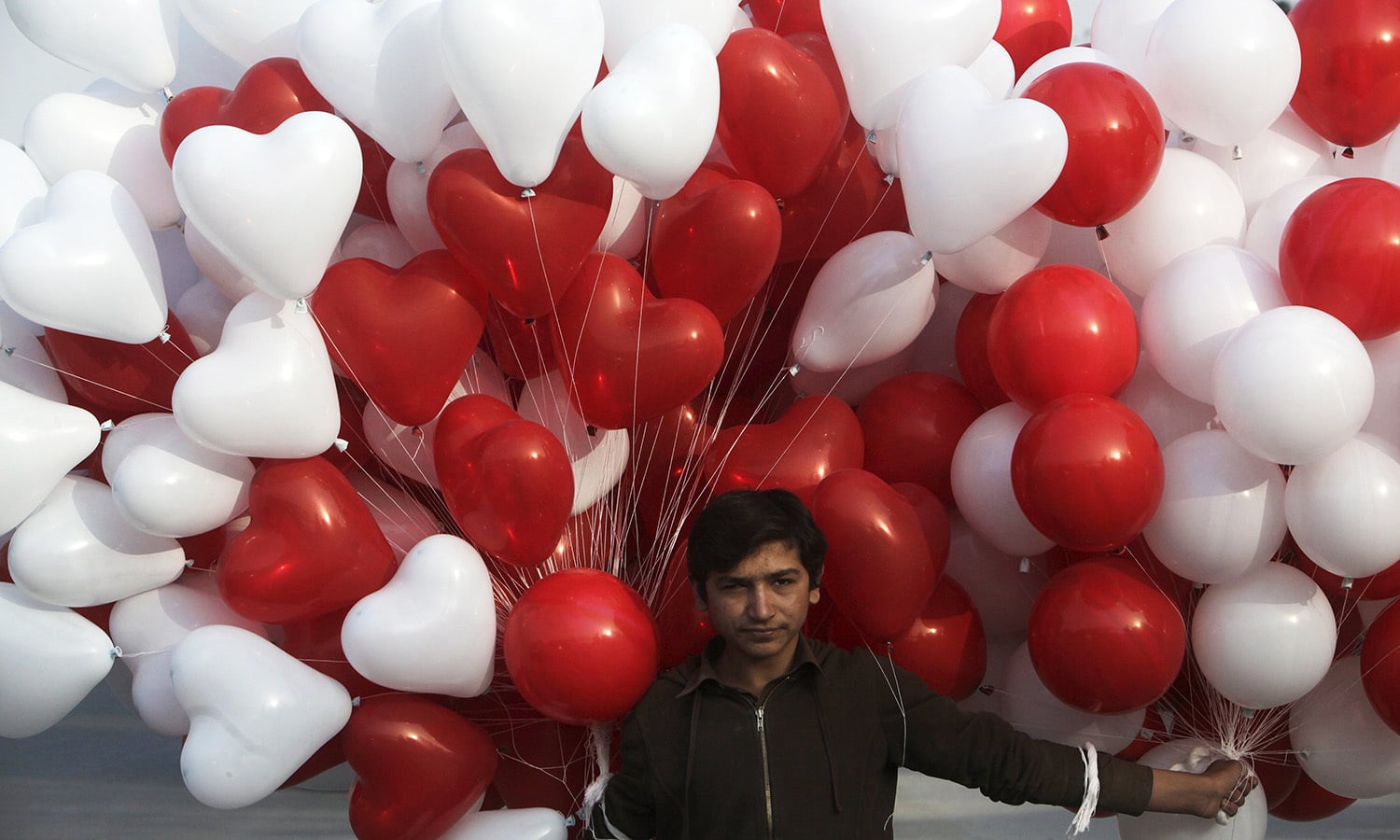 A vendor carries heart-shaped balloons for sale on Valentine's Day in Lahore.─Reuters