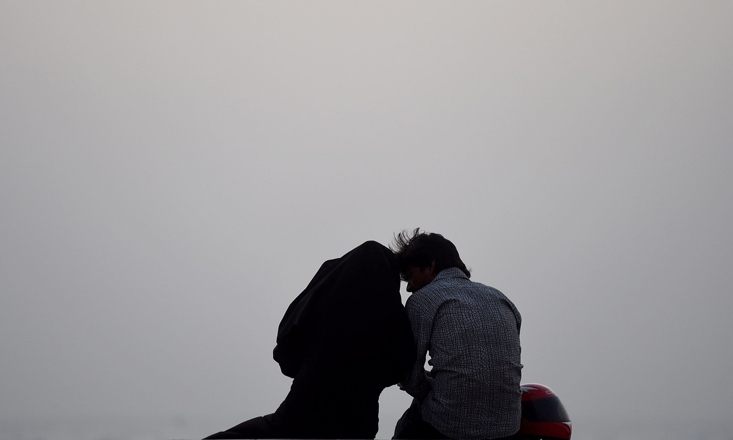 A Pakistani couple sits on a beach on Valentine's Day in Karachi.─AFP