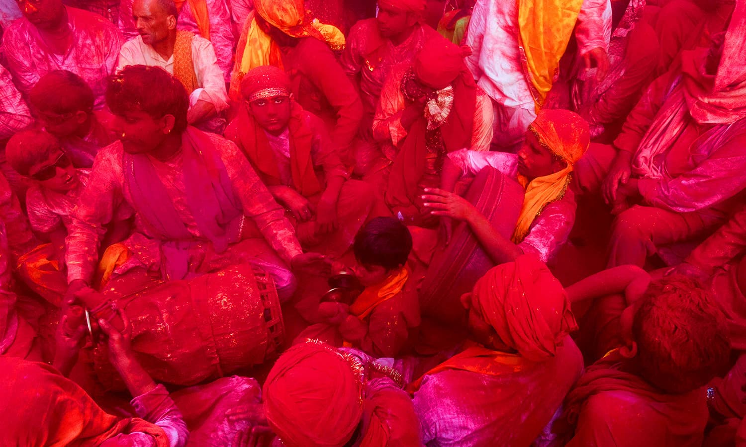 Indian villagers are covered with coloured powder during the Holi festival at the Radha Rani temple in Barsana. ─ AFP