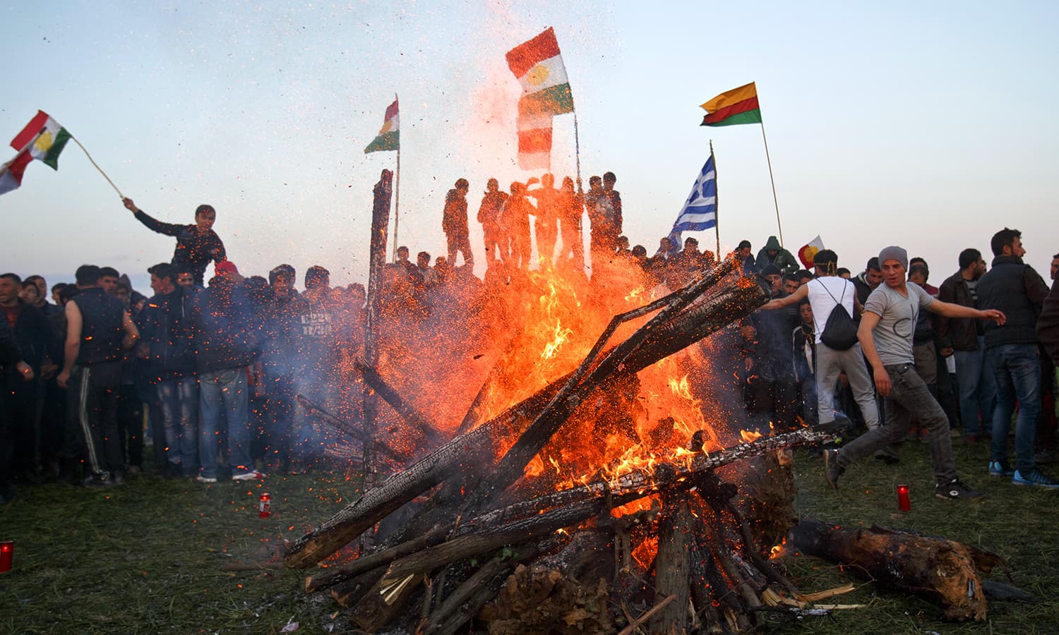 Burning wood collapses as Kurdish Syrians celebrate Nowruz at the northern Greek border point of Idomeni, Greece. ─ AP