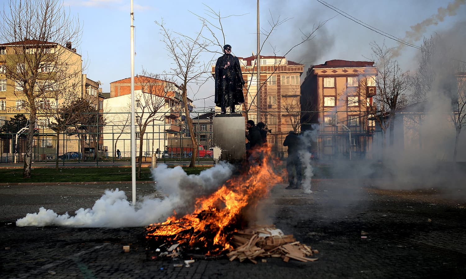 Demonstrators try to protect themselves near a barricade as they clash with security forces during banned Nowruz celebrations in Gazi district in Istanbul, Turkey. ─ AP