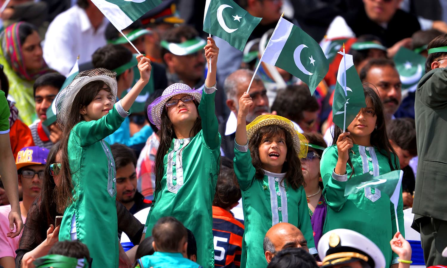 Young children wave flags as they watch the Pakistan Day military parade. ─ AFP