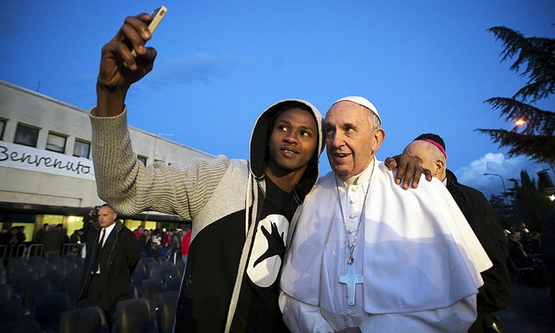 A refugee makes a picture with Pope Francis after the foot-washing ritual at the Castelnuovo di Porto refugees center near Rome, Italy, March 24, 2016.—Reuters