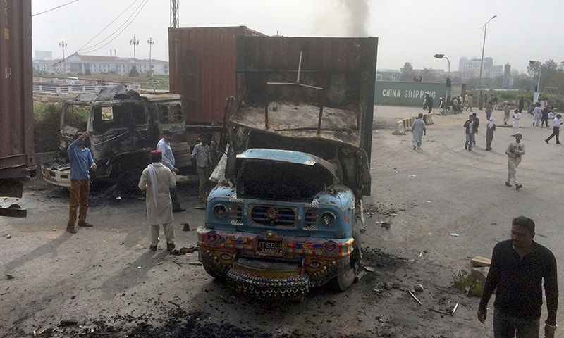 People look at trucks burnt by supporters of Sunni Tehreek during a march toward the parliament.─AP