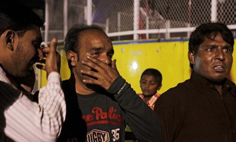 Men mourn the death of their relatives after a blast outside a public park in Lahore. — Reuters