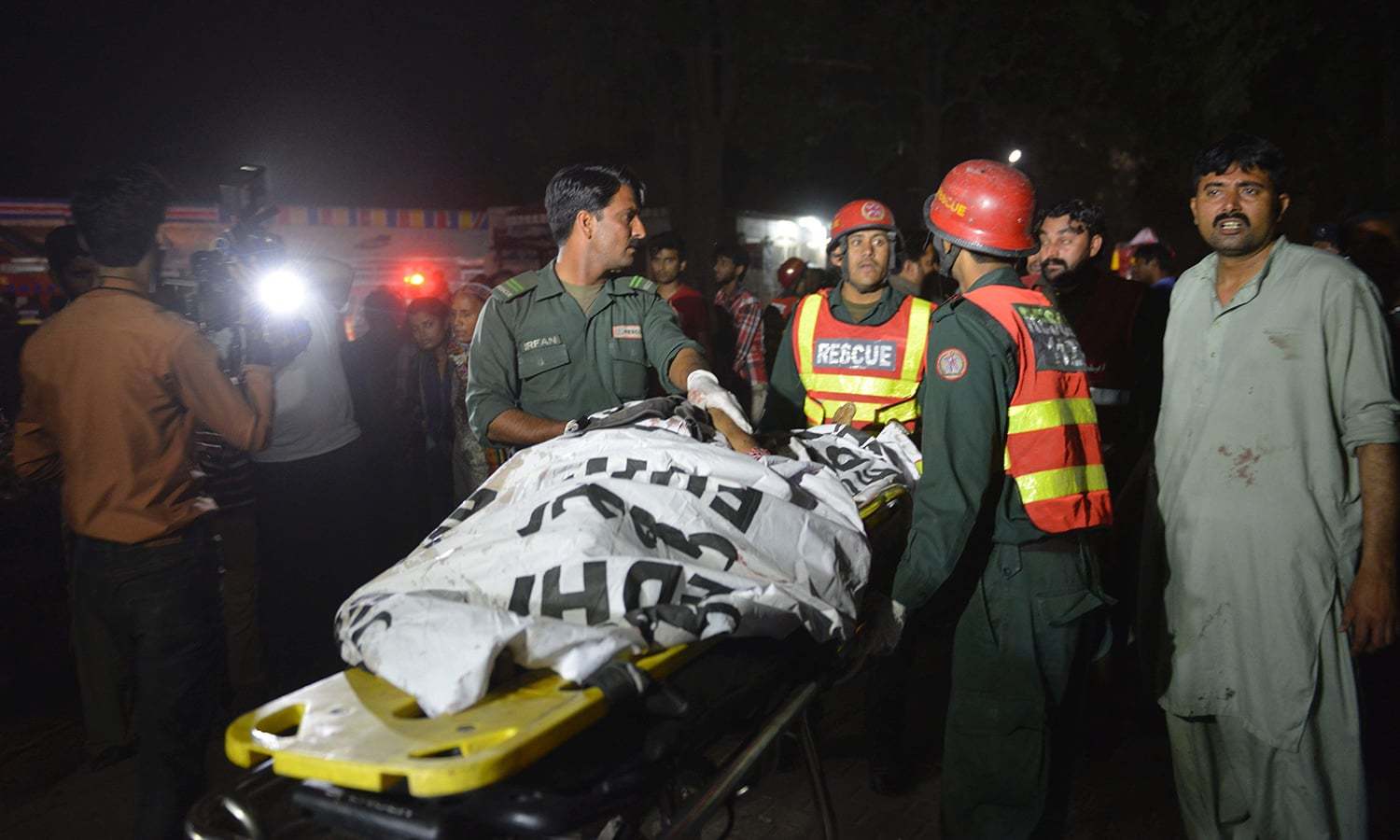 Rescuers use a stretcher to shift a body from a bomb blast site in Lahore.─AFP/File