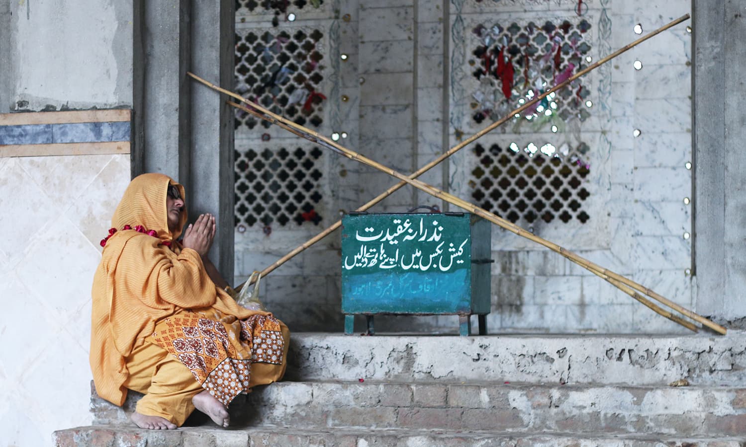 A woman sitting on the steps of the shrine of Sufi saint Madhu Lal Hussain.