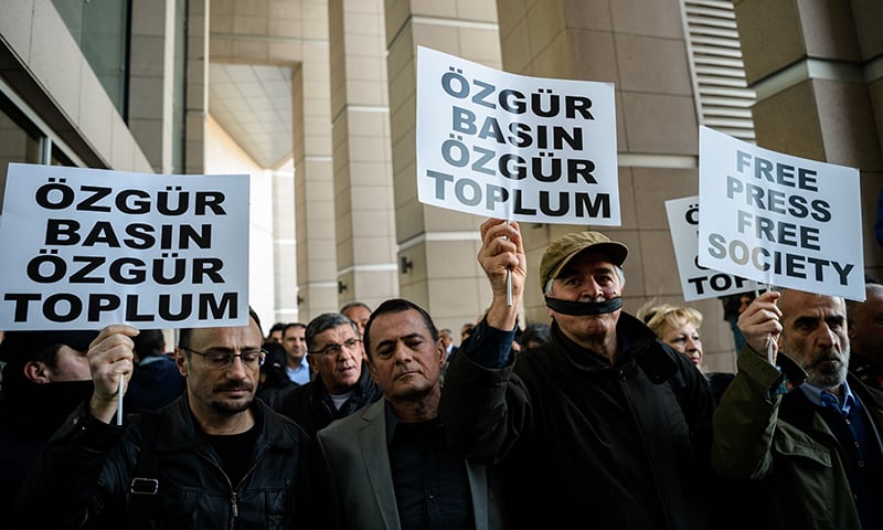 Demonstrators with their mouth covered, hold placards reading "Free Press Free Society", outside the Istanbul courthouse on April 1, 2016, where Turkish opposition Cumhuriyet daily's editor-in-chief Can Dundar and Ankara bureau chief Erdem Gul attend their trial.-AFP