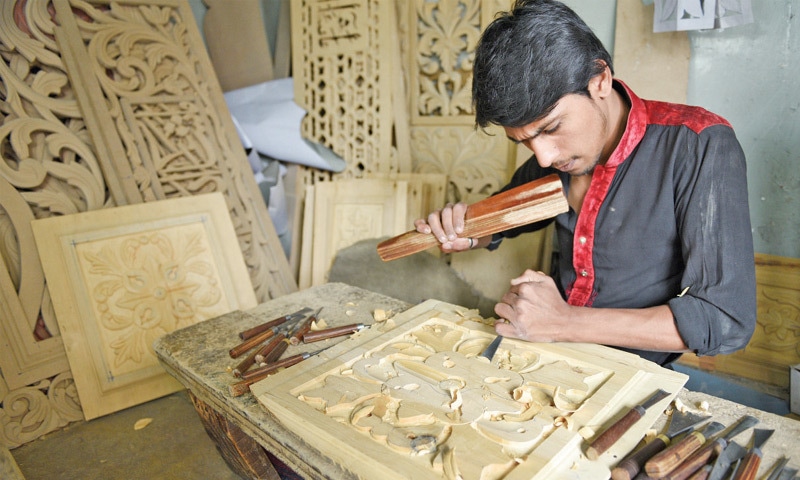 Fayyaz Ali chisels a wood panel at his workshop.