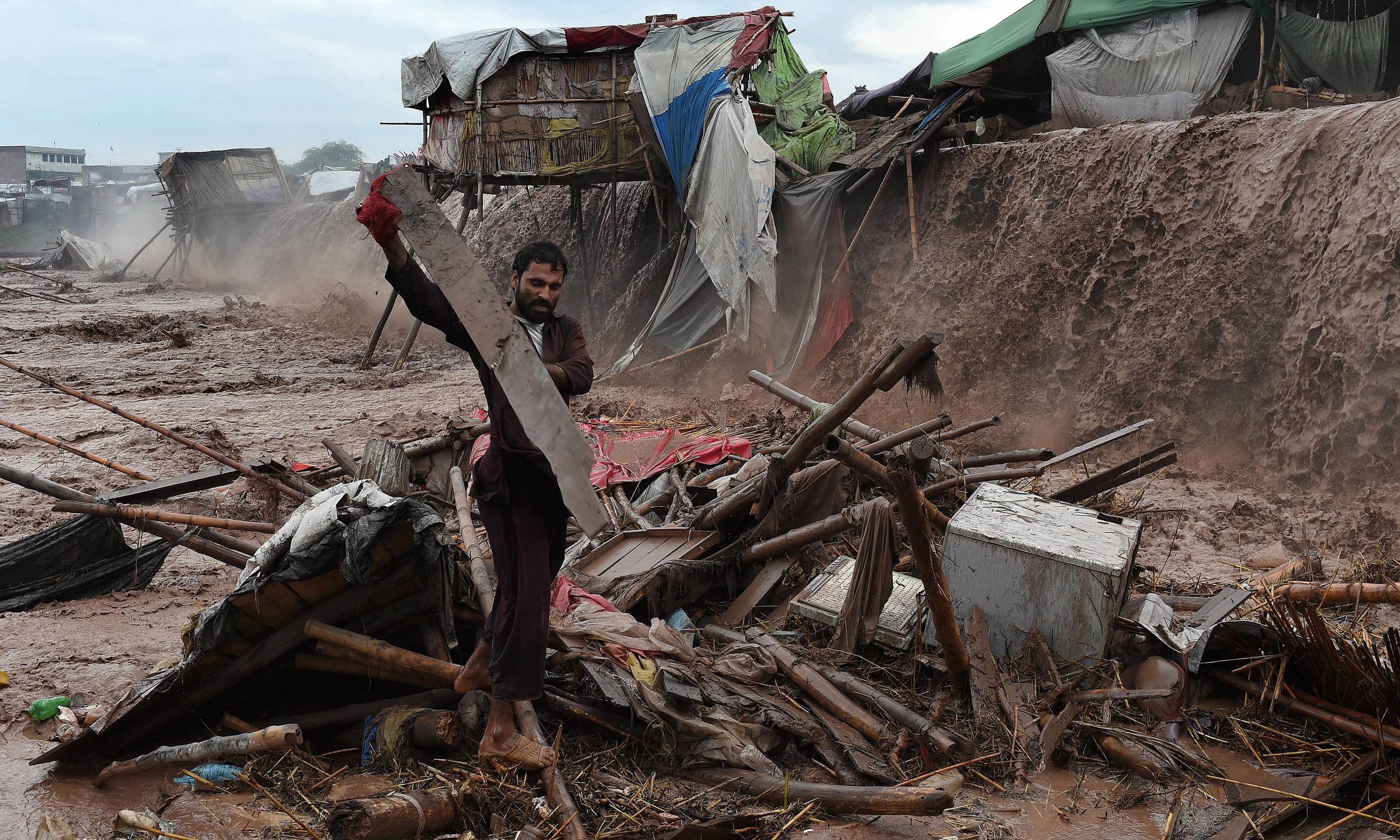 Flood waters rush through a market area as a man tries to salvage materials on the outskirts of Peshawar. AFP